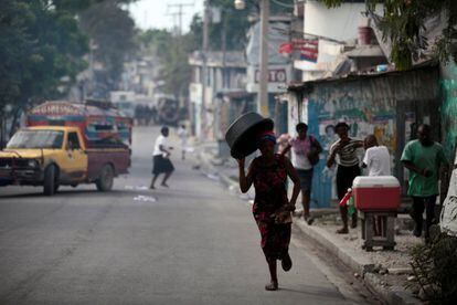 Una mujer intenta huir del gas lacrimógeno usado por la policía de Haití para dispersar una manifestación, en las calles de Puerto Príncipe.