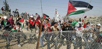 Decenas de manifestantes tratan de derribar hoy una sección de la polémica carrera israelí en el poblado de Bilin, cerca de Ramala