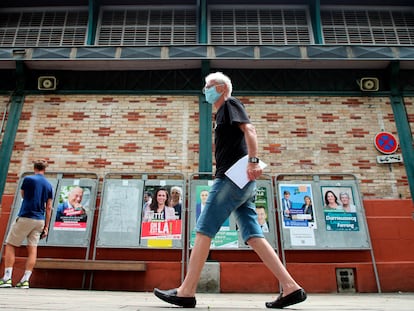 Un hombre camina en San Juan de Luz delante de carteles de las elecciones regionales francesas.