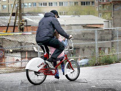 Un hombre con  un niña sentada en la barra de una bicicleta del <b>Bicing</b> en Barcelona.
