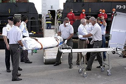 Policías y bomberos sacan a uno de los cadáveres encontrados en las bodegas del <i>Nathalie Bolten.</i>