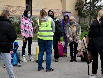 Varias personas refugiadas hablan con una traductora frente a la Fira de Barcelona