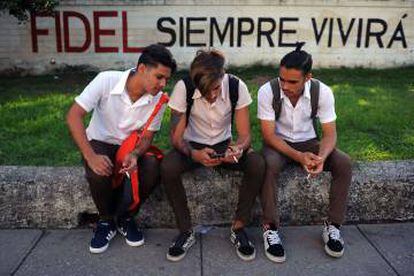 Jóvenes cubanos observan su celular.