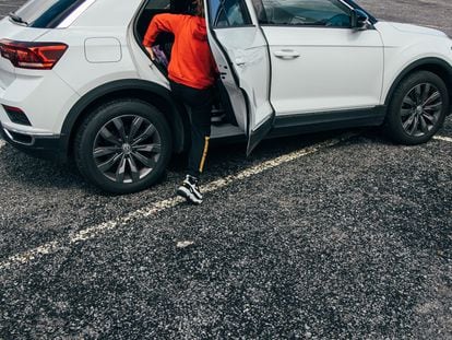 Un niño sube a un coche tipo SUV que sobresale de una plaza de aparcamiento en las afueras de Santiago de Compostela, este jueves.