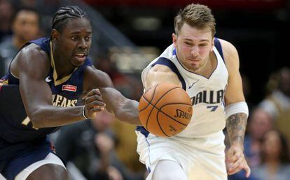 Doncic y Holiday pugnan por un balón.