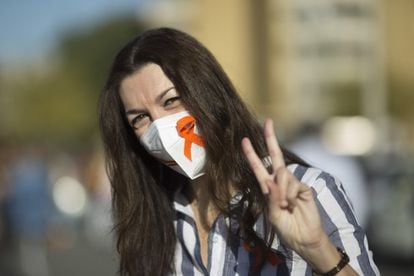 Una mujer con un lazo naranja en la mascarilla asiste a la protesta en la capital hispalense, este domingo.