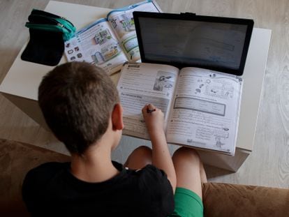 Un alumno de Primaria hace los deberes de la asignatura de Inglés con varios libros y un ordenador.