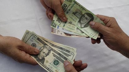 Dos personas intercambian dólares y pesos mexicanos.
