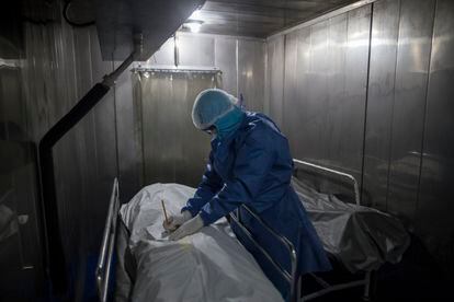 Un trabajador del hospital La Samaritana en Bogotá llena un formulario con los datos de una persona fallecida por covid-19 en la morgue de ese centro médico.