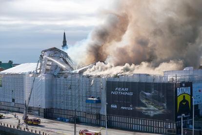 Nuvens de fumaça sobem sobre a Bolsa de Valores de Copenhague enquanto os bombeiros tentam apagar as chamas.