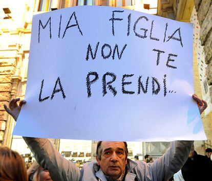 Un manifestante durante una protesta contra el primer ministro Silvio Berlusconi muestra una pancarta que dice: "A mi hija no la vas a coger"