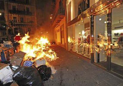 Un montón de basura arde frente a una tienda de la comercial Via Roma, en Nápoles (Italia), el viernes 24 de junio de 2011.