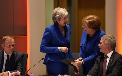 La primera ministra británica, Theresa May, y la canciller alemana, Angela Merkel, se ríen antes de que comience la reunión del Consejo Europeo. A la izquierda, el presidente del Consejo Europeo, Donald Tusk, mira a ambas jefas de Gobierno.