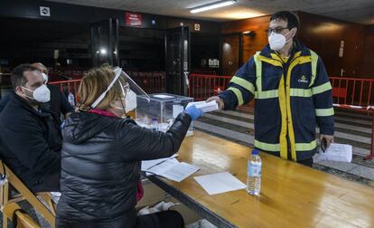 Un trabajador entrega los votos por correo en el pabellón municipal Fontajau, en Girona. Correos ha establecido un "despliegue logístico especial" integrado por 1.648 trabajadores para entregar los votos cursados por correspondencia en las mesas durante esta jornada electoral.