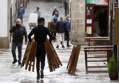 Un camarero trabaja en una terraza en una calle de Santiago de Compostela, donde se ha impuesto un máximo de cinco personas en las reuniones.