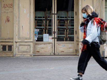 Una mujer pasea por París por delante de un restaurante cerrado.