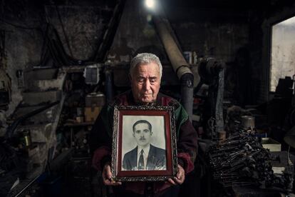 Rafael Gómez Pimpollo Sevilla posa en su fragua en Solana con la foto de su padre, Rafael Gómez-Pimpollo Serrano, asesinado en 1940 cuando él tenía dos años.