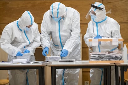 Un presidente de mesa y dos vocales vestidos con trajes de protección especial EPI, cuentan votos en el colegio electoral de Casal de Gent Gran de Gràcia.