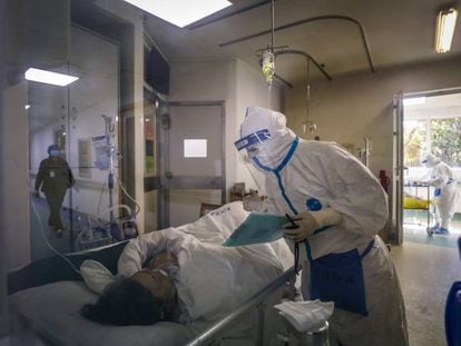 Un trabajador en un hospital de Wuhan atiende a una paciente afectada por el coronavirus.