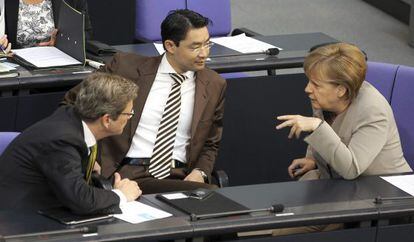 La canciller alemana, Angela Merkel, conversa con el ministro alemán de Exteriores, Guido Westerwelle (izda), y el ministro alemán de Economía, Phillip Rösler (centro), durante una sesión parlamentaria en Berlín.