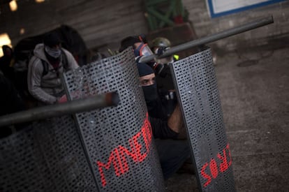 Mineros, parapetados tras una plancha metálica, lanzan artefactos caseros contra posiciones de la policía en la mina El Sotón.