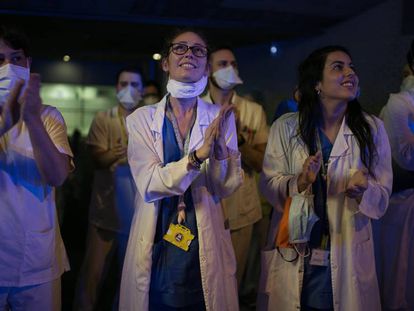 Varios profesionales sanitarios aplauden a las ocho de la tarde a las puertas del Hospital de Sant Pau, en Barcelona, el domingo.