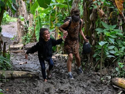 A Venezuelan migrant girl is helped by her mother as they arrive at Canaan Membrillo village, the first border control of the Darien Province in Panama, on October 13, 2022. - The clandestine journey through the Darien Gap usually lasts five or six days at the mercy of all kinds of bad weather: snakes, swamps and drug traffickers who use these routes to take cocaine to Central America. (Photo by Luis ACOSTA / AFP) / TO GO WITH AFP STORY BY JUAN JOSE RODRIGUEZ