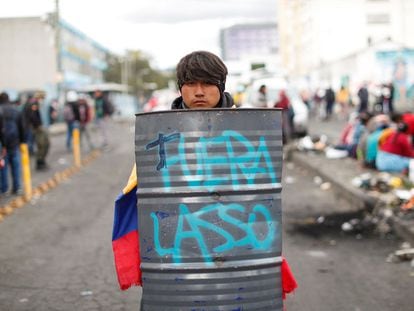 Cesar llumiquinga posa con un escudo de chapa con la pintada "Fuera Lasso" este domingo en Quito.