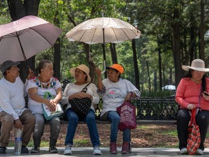 Personas se protegen de las altas temperaturas en la Alameda Central, en Ciudad de México, en junio de 2023.