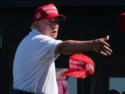 El expresidente Donald Trump lanza gorras con su autógrafo a sus seguidores, en una imagen del pasado domingo en Bedminster, Nueva Jersey.