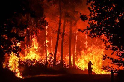 Una persona frente a las llamas en un incendio forestal cerca de Belin-Beliet, suroeste de Francia, durante la madrugada de este jueves.