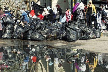 Un grupo de voluntarios recoge bolsas de basura en la plaza de la Liberación de El Cairo.