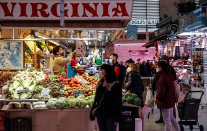 Several people shop at a fruit and vegetable stall in the Central Market of Valencia.