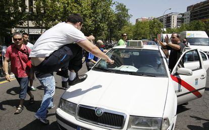 Un manifestante salta en el capó de un taxi que estaba trabajando durante la protesta del sector del taxi por las calles de Madrid.