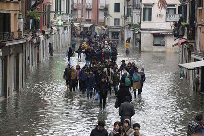 Los turistas pasean por Venecia, en una calle inundada por el 'acqua alta'.