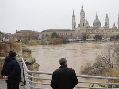 Varios vecinos de Zaragoza observan la crecida del río Ebro, este martes.