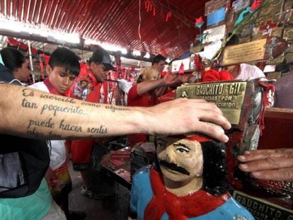 Un hombre apoya su mano sobre una imagen del Gauchito Gil en el santuario de Corrientes.