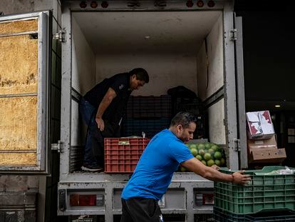 Repartidores de alimentos descargan cajas de verdura en el centro histórico de Ciudad de México.