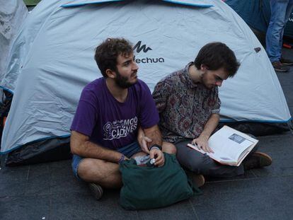 Dos estudiants llegeixen davant la tenda de camapanya, instal·lada aquest dimecres a la plaça Universitat de Barcelona.