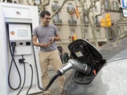 Un usuario de un veh&iacute;culo el&eacute;ctrico lo recarga en el paseo de Gr&agrave;cia de Barcelona.