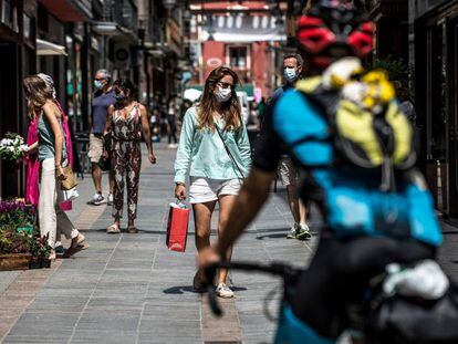 Varias personas protegidas con mascarilla pasean por una de las calles comerciales de Puigcerdà.