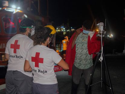 Dos personas de Cruz Roja atienden a un joven llegado en patera al puerto de Motril el pasado 10 de agosto.