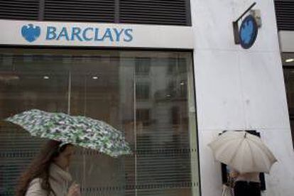 Una mujer con un paraguas pasando delante de una sucursal del banco Barclays en Londres, Reino Unido, el pasado 2 de julio. EFE/Archivo
