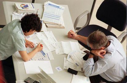 Dos personas rellenan los impresos en una delegación de Hacienda.