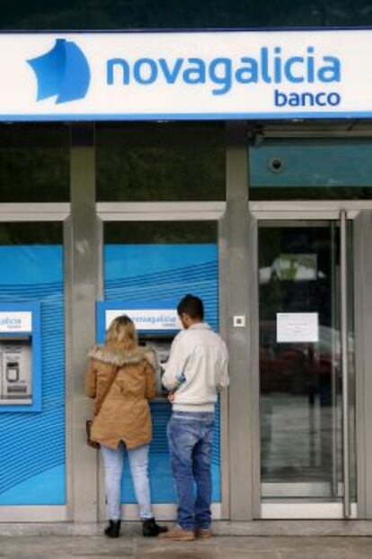 Dos j&oacute;venes retiran dinero de un cajero en una sucursal de Novagalicia Banco. 