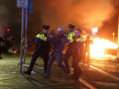 Tres agentes de policía detienen a uno de los manifestantes durante la noche del jueves en Dublín.