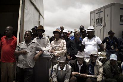 Un grupo de hombres sudafricanos sigue el entierro de Mandela desde una colina a través de una pantalla gigante en Qunu.