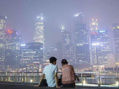 Una pareja observa los rascacielos cubiertos de humo en Singapur.