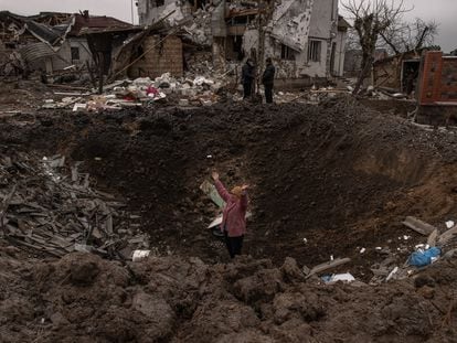 Una mujer en uno de los cráteres provocados por los misiles rusos en Hlevakha, a unos 30 kilómetros de Kiev, este jueves.