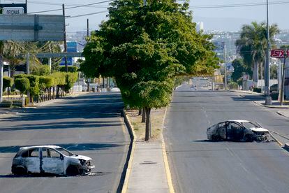 Un par de vehículos calcinados en una calle desierta, luego de los enfrentamientos entre grupos armados y las fuerzas de seguridad, en Culiacán, este jueves.